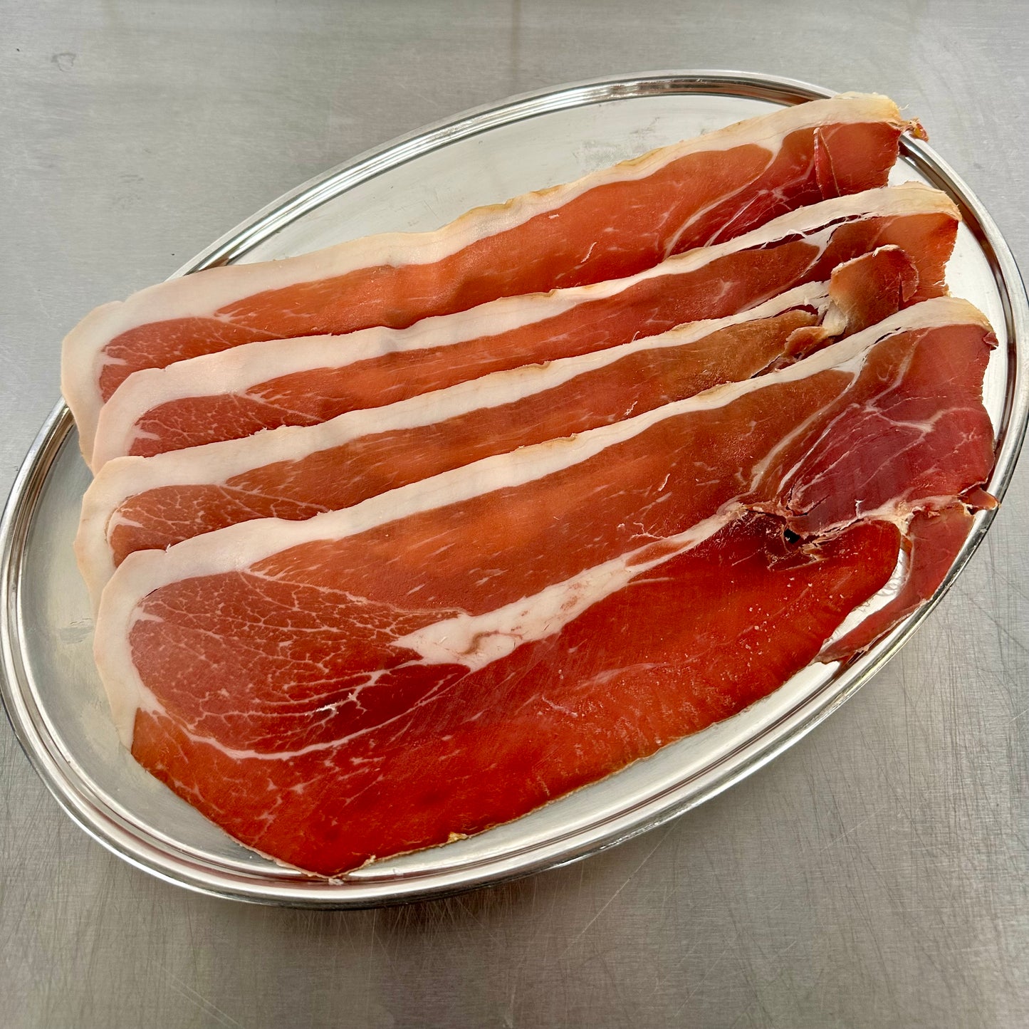 24 month aged Jambon slices on a metal tray with a gray background