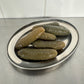 Cornichons on a metal tray with a tiled wall background